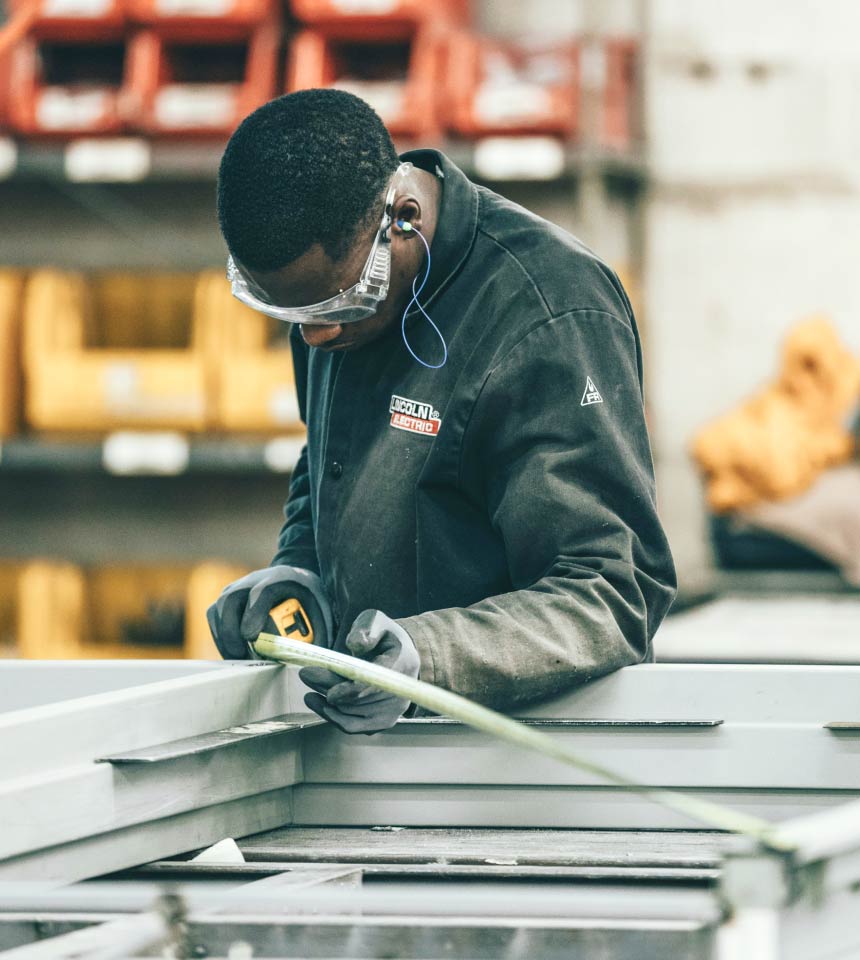 Services 2 Man Using Measuring Tape in Factory Setting